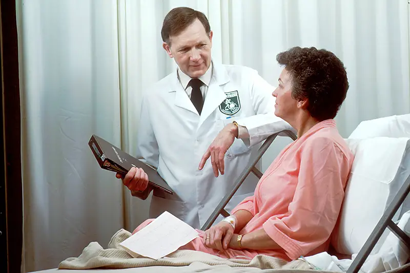 doctor holding a brown record book beside a patient