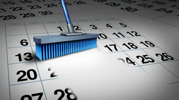 Clear your schedule business concept and reduce a work week symbol as a broom erasing a calendar as a deadline timetable metaphor for time management or appointment cancelation.