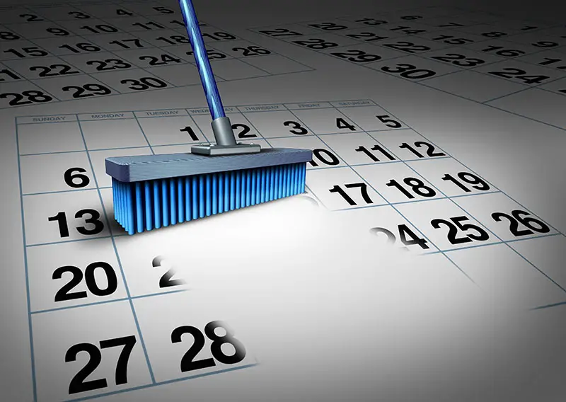 Clear your schedule business concept and reduce a work week symbol as a broom erasing a calendar as a deadline timetable metaphor for time management or appointment cancelation.