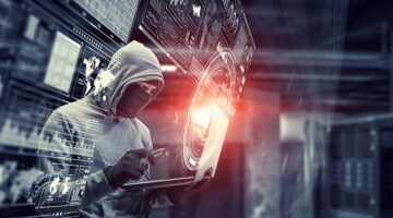 Computer hacker in hoodie and mask stealing data from laptop