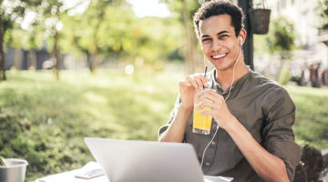 happy man sitting with laptop and juice in the park