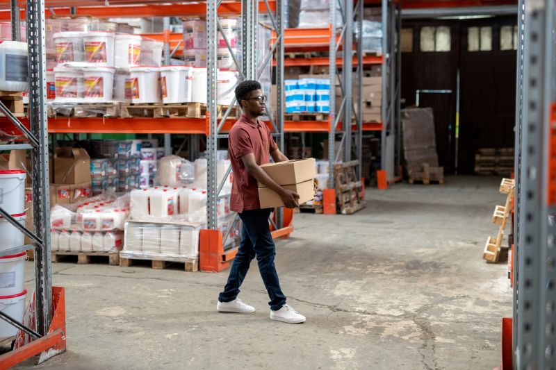 Black guy carrying boxes at warehouse