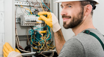 electrician repairing electrical box with pliers in corridor