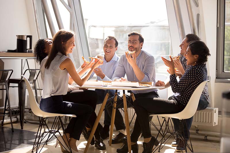 happy diverse team workers talking laughing eating pizza together in office