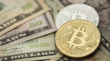 Golden and silver bitcoin over dollar bills