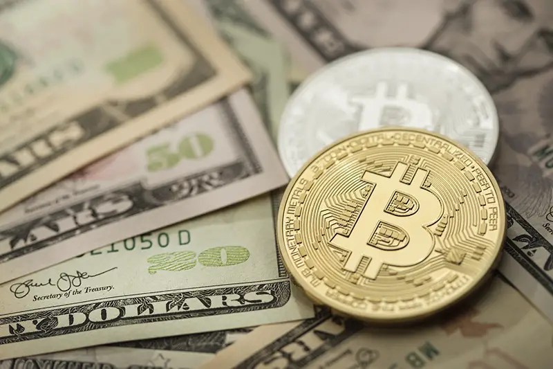 Golden and silver bitcoin over dollar bills