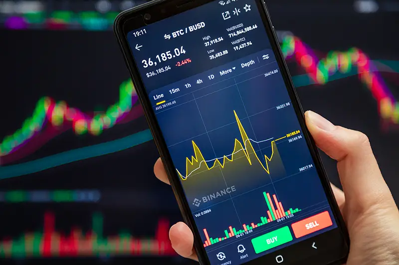 Binance mobile app running at smartphone screen with a trading page at background