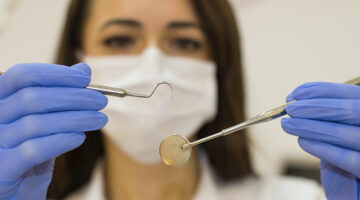 Female dentist wearing facemask and blue rubber gloves