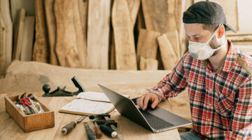 Man using a laptop at a wood workshop