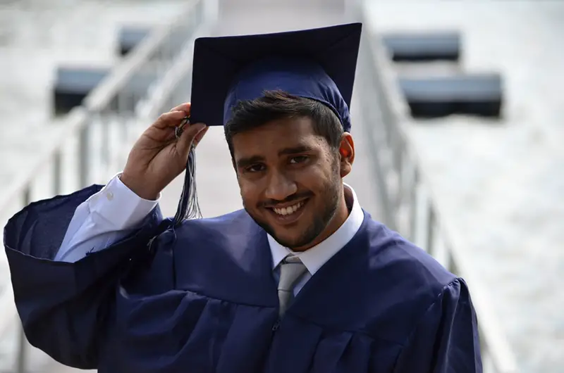 Happy young man wearing graduation gown