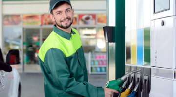 Smiling worker at the gas station, while filling a car