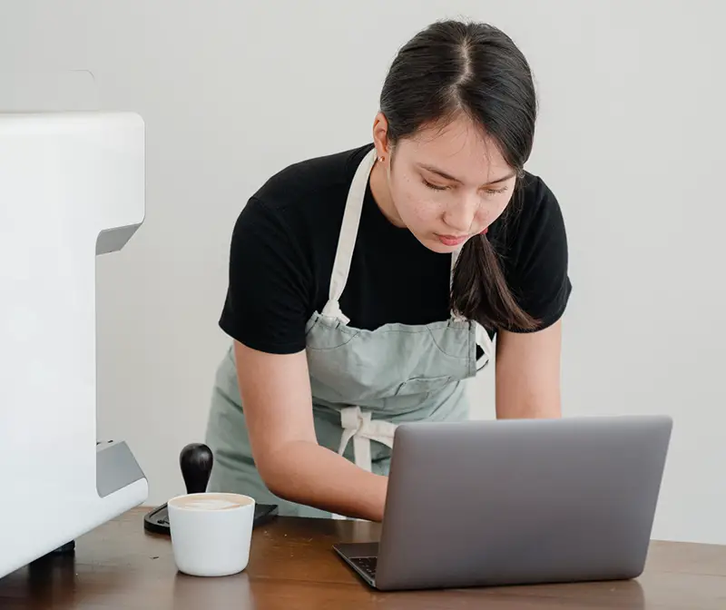 Concentrated barista using laptop at workplace