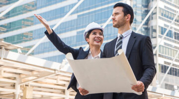 à¸ºBeautiful architect wore a suit and helmet, standing and talking to a male businessman in a real estate construction project.Estate Property Development concept.