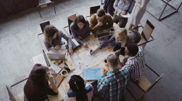 Top view of mixed race business team sitting at the table at loft office
