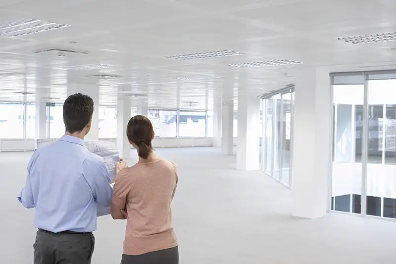 Rear view of businessman and businesswoman looking at plan and empty office building