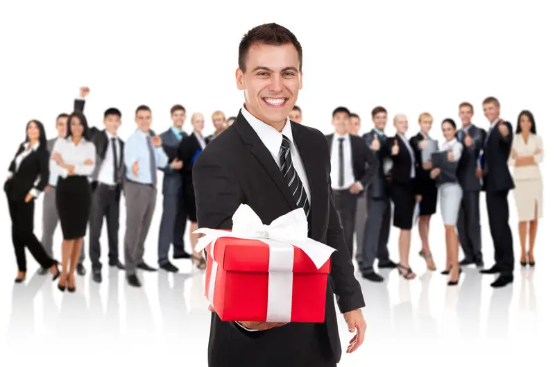 Businessman holding a gift wrapped in red box with white ribbon