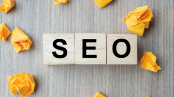 SEO (Search Engine Optimization) text wood cubes with crumbled paper on wooden table background.