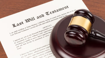 Last will and testament on yellowish paper with wooden judge gavel; document is mock-up