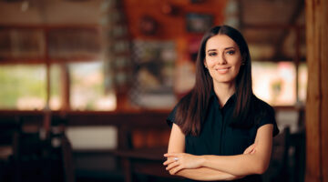 Manager Standing in a Restaurant Welcoming Customers.