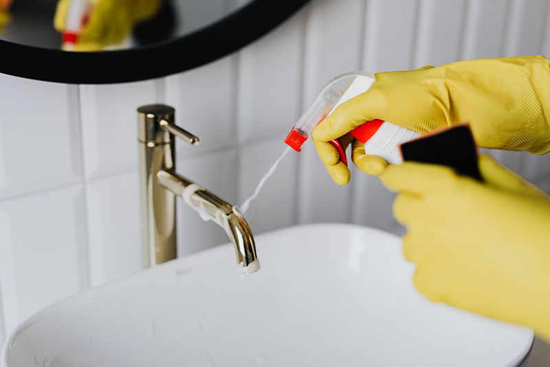 Cleaner wearing yellow gloves tiding up bathroom