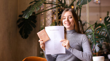 Young woman holding passport and visa application at travel agency