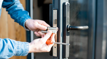 Man changing core of a door lock of the entrance glass door