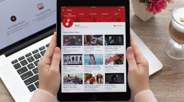 Woman holding a iPad Pro Space Gray with video sharing website YouTube on the screen.