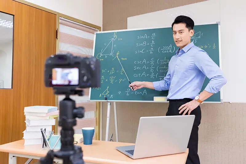male teacher teach math online through camera in classroom