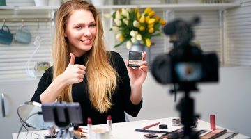 Beauty blogger woman filming daily make-up routine tutorial near camera