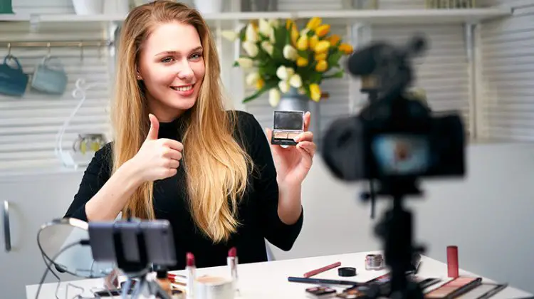 Beauty blogger woman filming daily make-up routine tutorial near camera