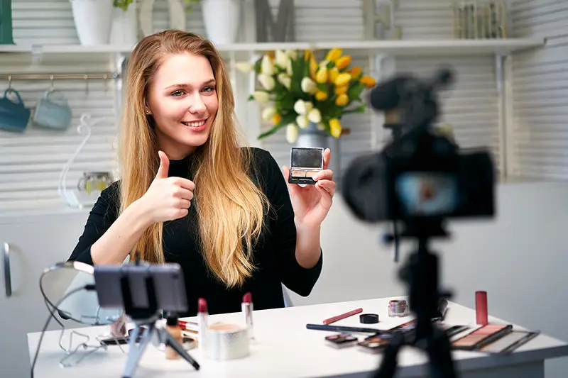 Beauty blogger woman filming daily make-up routine tutorial near camera