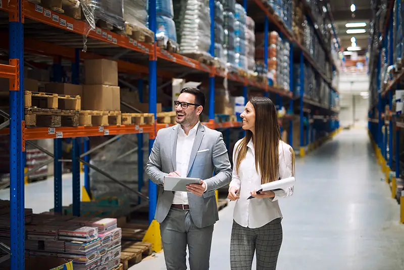 Two successful business people walking through large warehouse center