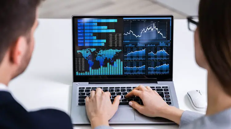 Two Businesspeople Analyzing Financial Graph On Laptop