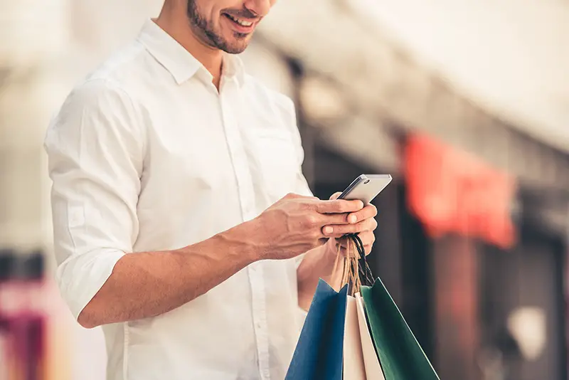 Man with shopping bag using his smartphone