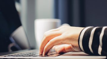 Female hands typing on keyboard of computer laptop