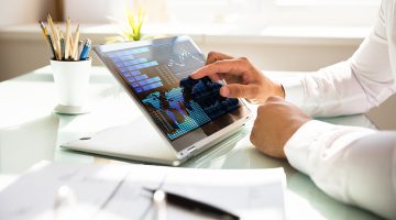 Close-up of a businessman's hand analyzing graph on laptop