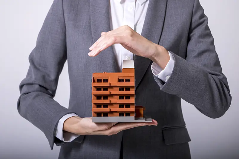 business person holds apartment building miniature model