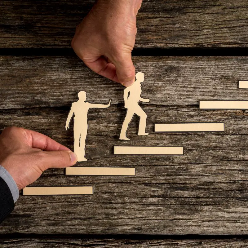 Career path concept with the hands of two businesspeople supporting paper cut outs