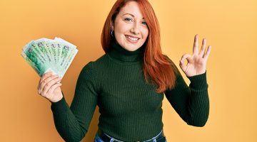 Woman smiling while holding Singaporean dollar bills