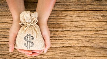 Women hold a money bag on the vintage wood background