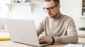 Man with eyeglasses focused working on his laptop computer