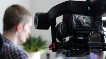 Black Video Camera Turn on Next to Man Wears Polo shirt