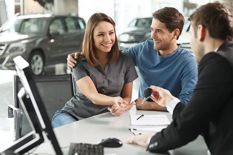 Couple talking to a male car sales agent
