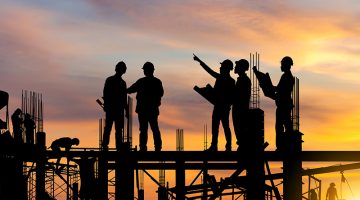 Silhouette of Engineer and worker on building site, construction site at sunset in evening time.