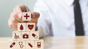 Businessman hand arranging wood block stacking with icon healthcare medical