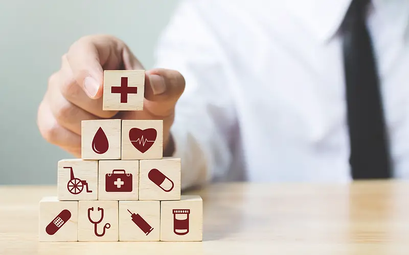 Businessman hand arranging wood block stacking with icon healthcare medical