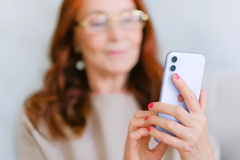 Elderly woman messaging on modern smartphone