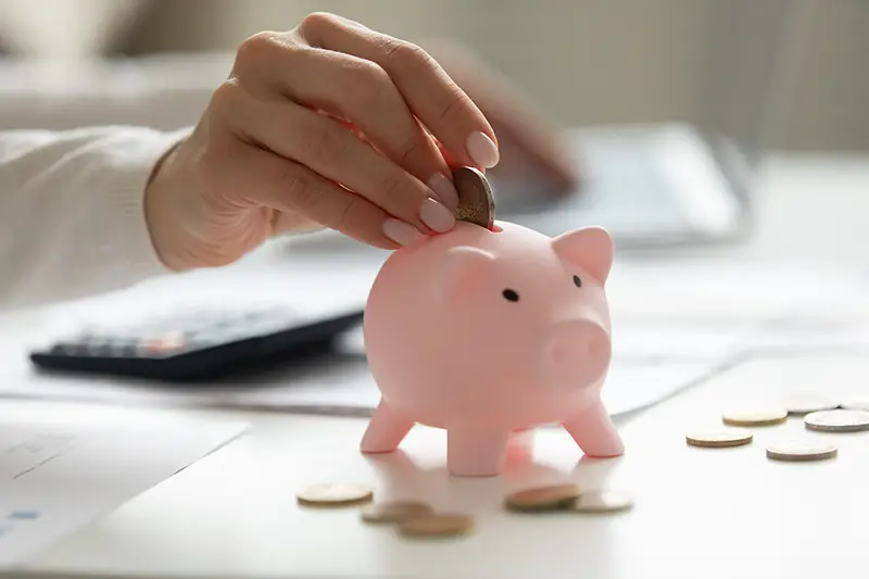Woman putting coin in pink piggy bank