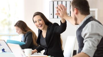 Two happy coworkers celebrating success giving five at office