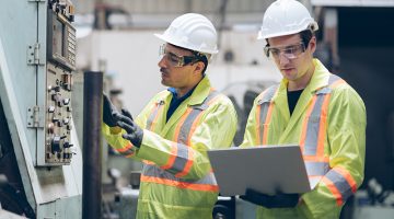 technician engineer and mentor checking process on laptop to automated CNC in factory